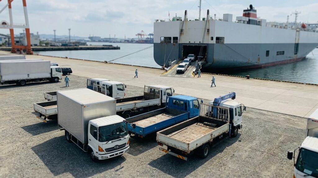 岸壁に並ぶ中古トラックと自動車専用船